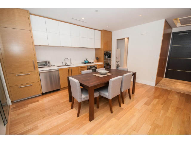 Bright kitchen with white cabinets, stainless steel appliances, and hardwood floors. - 1701 - 667 Howe Street, Vancouver Downtown