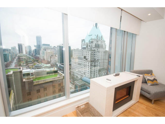 Bright living room with city view, modern fireplace, hardwood floors, and cozy seating. - 1701 - 667 Howe Street, Vancouver Downtown