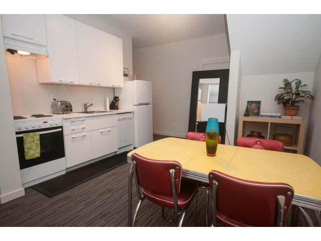 Bright kitchen with white cabinets, yellow countertops, and red chairs. - Suite - 1252 Duncan St, West Vancouver