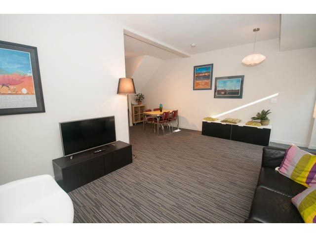 Furnished living room with modern decor, large windows, and a cozy corner. - Suite - 1252 Duncan St, West Vancouver