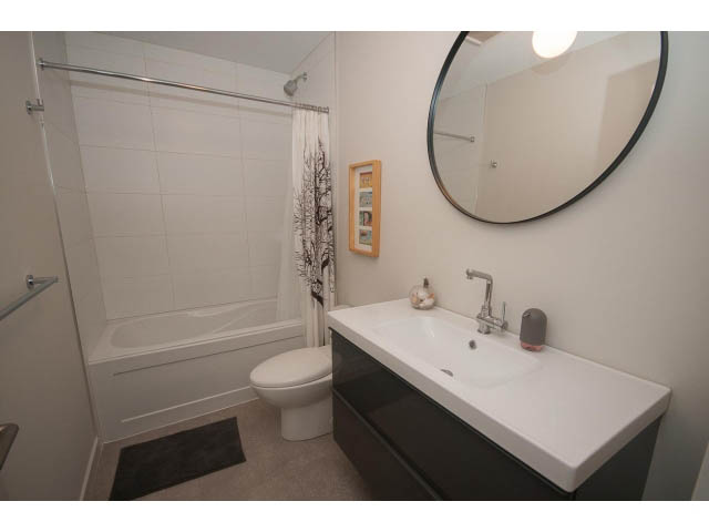 Bright bathroom with white countertops and a round mirror. - Suite - 1252 Duncan St, West Vancouver