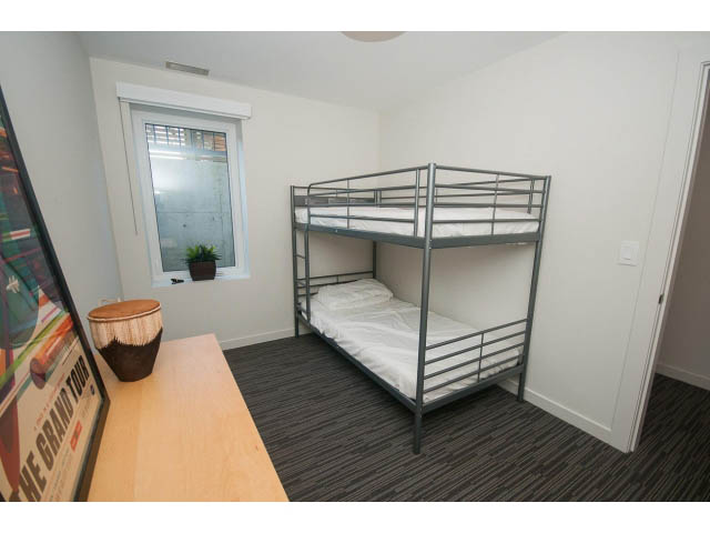 Bright bedroom with bunk beds, wooden floors, and a window view. - Suite - 1252 Duncan St, West Vancouver