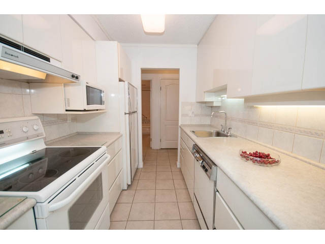 Bright kitchen with white cabinets, granite countertops, and stainless steel appliances. - 606 - 2020 Fullerton Ave, North Vancouver