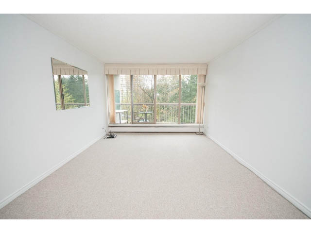 Spacious living room with large windows and carpeted floor. - 606 - 2020 Fullerton Ave, North Vancouver