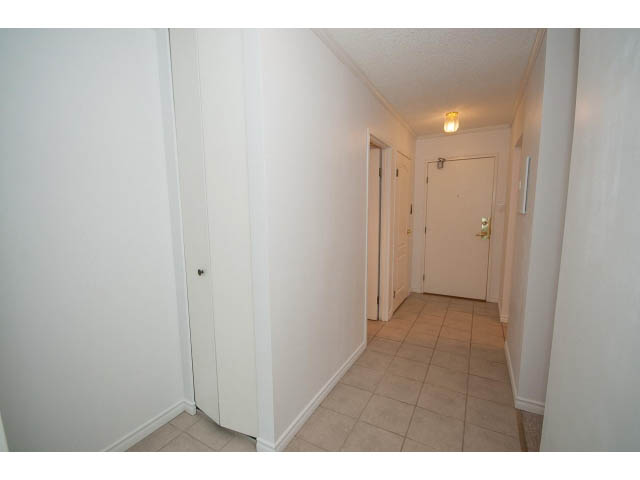 Bright hallway leading to bedrooms with white walls and tiled floors. - 606 - 2020 Fullerton Ave, North Vancouver