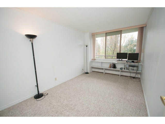 Bright living room with carpeted floor, floor lamp, and sliding glass door leading to balcony. - 606 - 2020 Fullerton Ave, North Vancouver