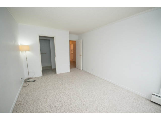 Bright living room with carpeted floors and white walls. - 606 - 2020 Fullerton Ave, North Vancouver