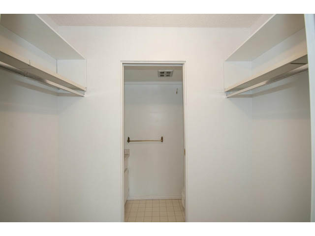 Walk-in closet with white shelves and a hanging rod. - 606 - 2020 Fullerton Ave, North Vancouver