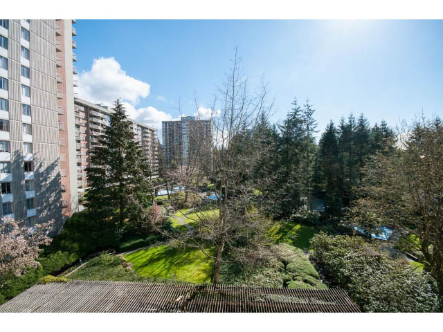 Bright living room with city view and lush greenery. - 606 - 2020 Fullerton Ave, North Vancouver