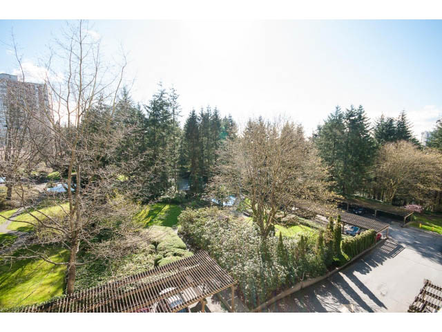 Bright living room with city view and lush greenery. - 606 - 2020 Fullerton Ave, North Vancouver