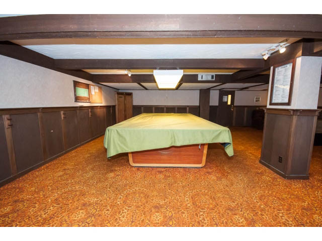Furnished living room with patterned carpet and built-in shelving. - 606 - 2020 Fullerton Ave, North Vancouver