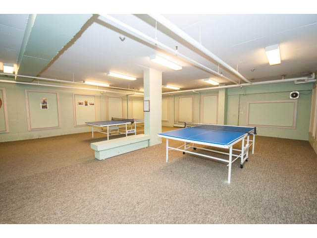 Furnished living room with ping pong tables and carpeted floors. - 606 - 2020 Fullerton Ave, North Vancouver
