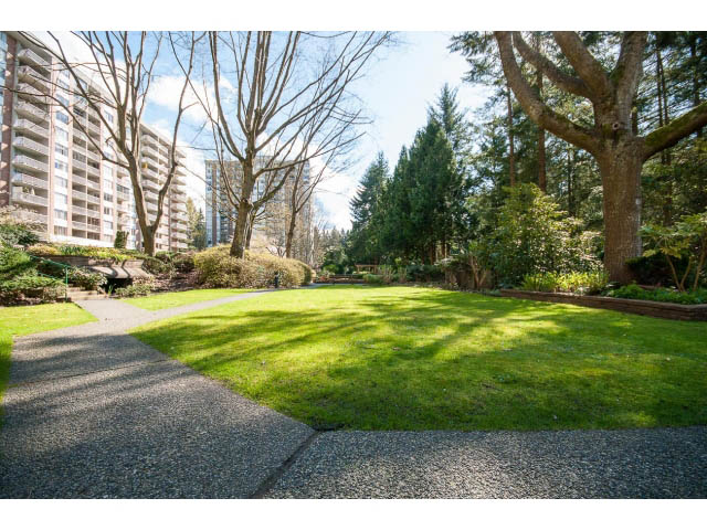 Furnished living room with green lawn and trees, city view in background. - 606 - 2020 Fullerton Ave, North Vancouver