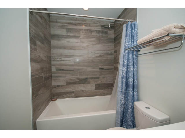 Furnished 1-bedroom condo bathroom with white tub, blue patterned shower curtain, and towel rack. - 317 - 311 East 6th Avenue, Vancouver East Side