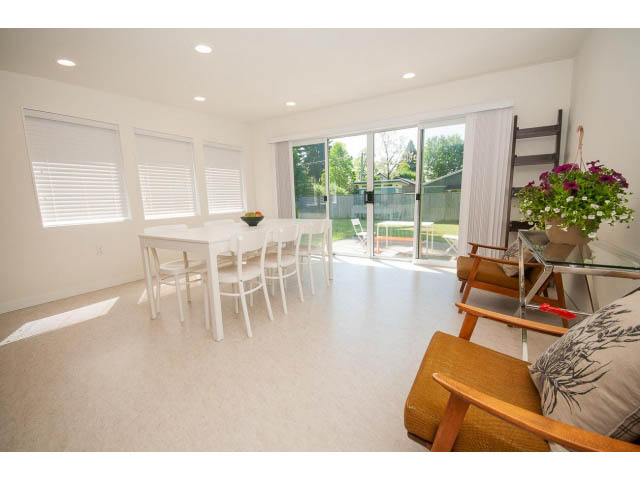 Bright dining area with sliding glass door, white blinds, and a cozy corner sofa. - 753 East 15th St, North Vancouver