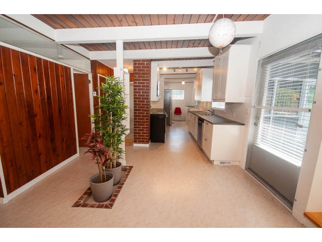 Bright kitchen with white countertops and hardwood floors, leading to a cozy living area. - 753 East 15th St, North Vancouver
