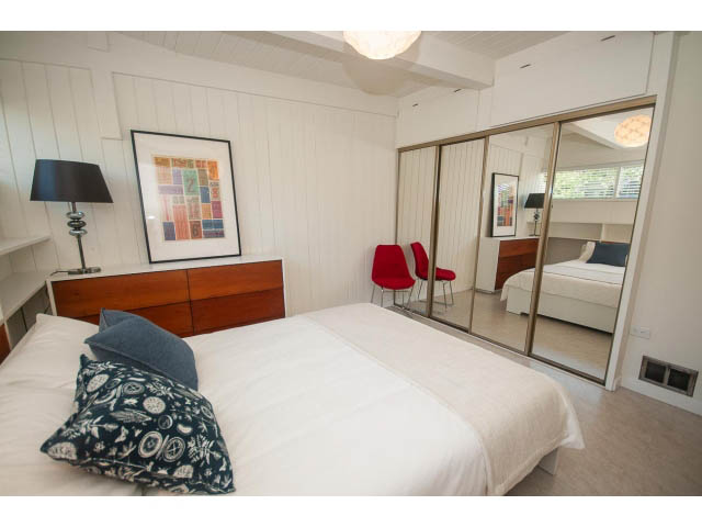 Furnished bedroom with white walls, modern furniture, and a city view through sliding glass doors. - 753 East 15th St, North Vancouver