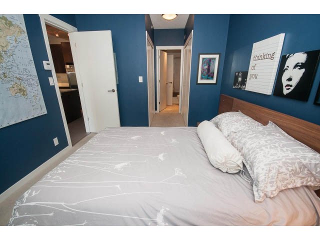 Furnished bedroom with blue walls, white bedding, and a "thinking of you" sign on the wall. - 203 - 135 West 2nd Street, North Vancouver