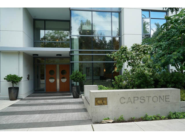 Furnished 1-bedroom + den with modern glass doors and concrete steps leading to entrance. - 203 - 135 West 2nd Street, North Vancouver