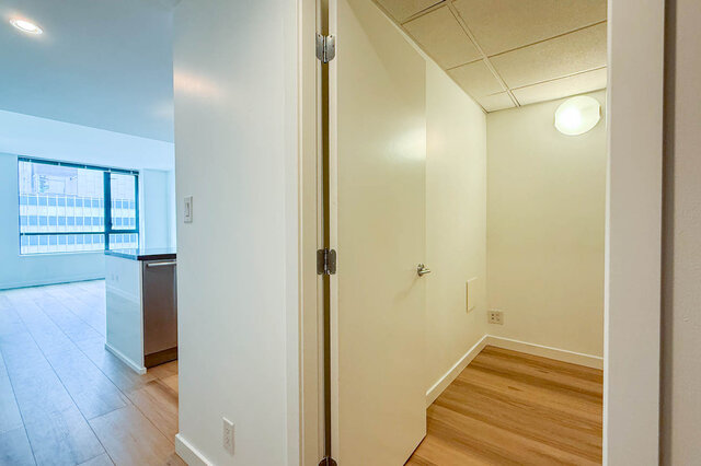 Small den with hardwood floors and a drop ceiling, adjacent to a kitchen with a window view. - 1904-788 Richards Street, Vancouver Downtown