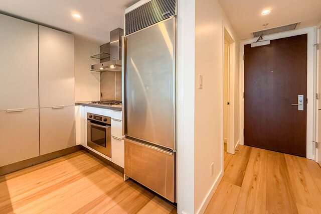 Compact kitchen with white cabinetry, stainless steel appliances, and light hardwood flooring. - 1904-788 Richards Street, Vancouver Downtown