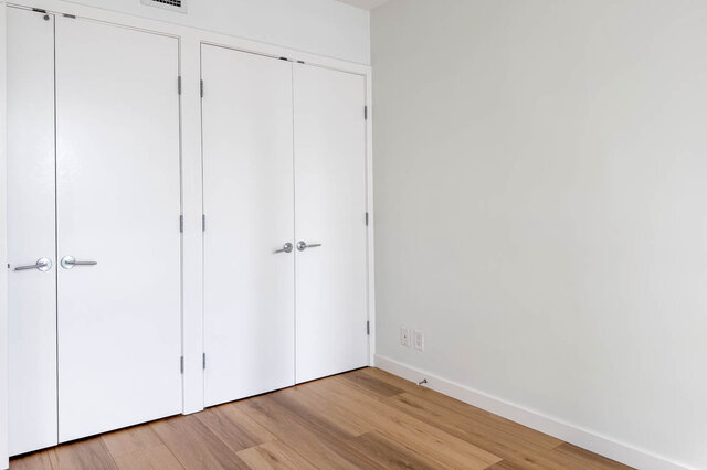 Empty den with light hardwood floors and a row of white paneled doors. - 1904-788 Richards Street, Vancouver Downtown