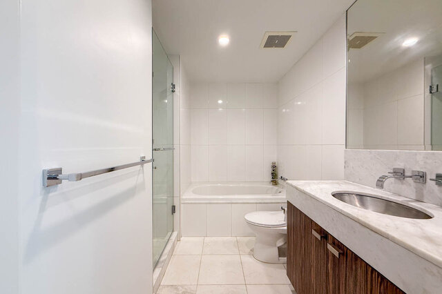 Clean bathroom with white tile, marble countertop, dark wood vanity, and a glass-enclosed tub/shower. - 1904-788 Richards Street, Vancouver Downtown