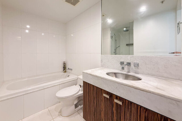 Bathroom with white tile walls, marble countertop vanity, and wood-grain cabinet. - 1904-788 Richards Street, Vancouver Downtown