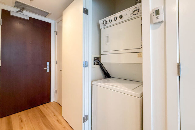 Entry hallway with hardwood floors and a stacked washer-dryer unit tucked into a white closet. - 1904-788 Richards Street, Vancouver Downtown