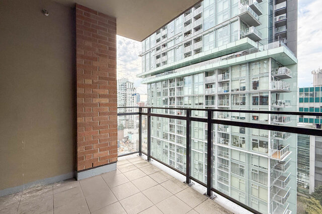 Balcony with tiled flooring and a brick accent wall overlooking a glass high-rise condo. - 1904-788 Richards Street, Vancouver Downtown