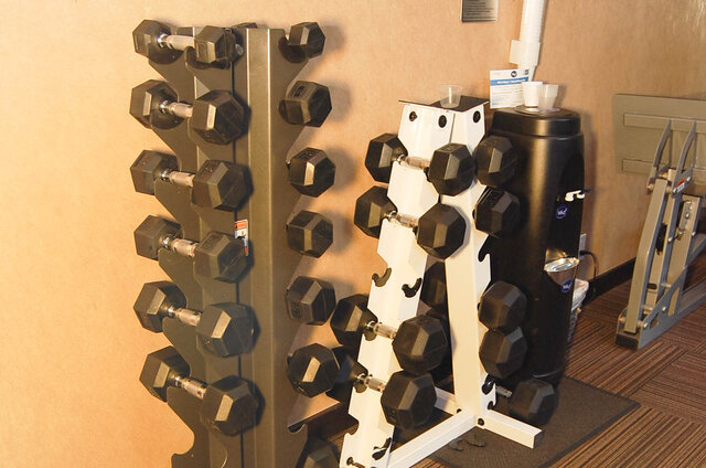 Compact in-unit gym with dual dumbbell racks and a water cooler on carpeted flooring. - 1904-788 Richards Street, Vancouver Downtown