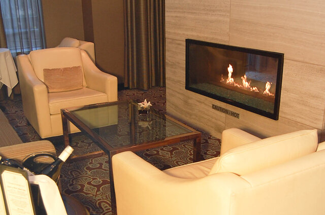 Cozy living room with cream leather armchairs, a glass coffee table, and a wall-mounted linear gas fireplace.
