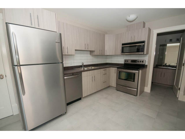 Bright kitchen with modern stainless steel appliances, light wood cabinets, and white tiled backsplash. - 3921 West 10th, Vancouver West Side
