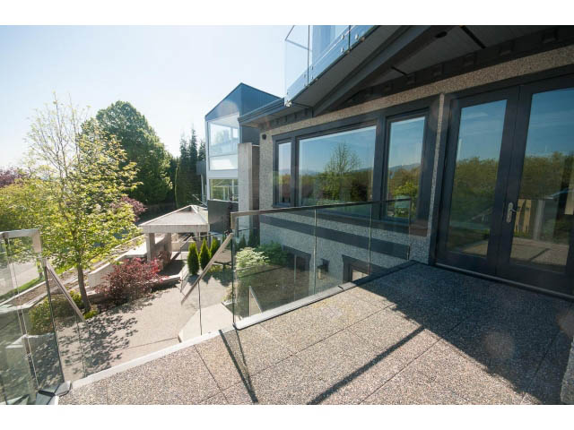 Bright living room with large glass doors, modern furnishings, and a view of the surrounding greenery. - 3921 West 10th, Vancouver West Side