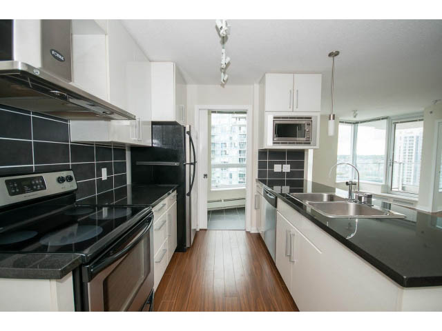 Bright kitchen with black countertops, hardwood floors, and city view. - 3006 - 188 Keefer Place, Vancouver Downtown