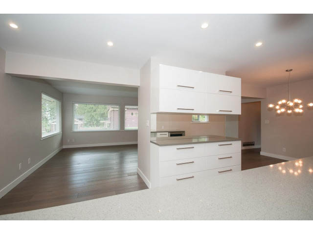 Bright kitchen with white cabinets, granite countertops, and hardwood floors. - 3188 St. Andrews Ave, North Vancouver