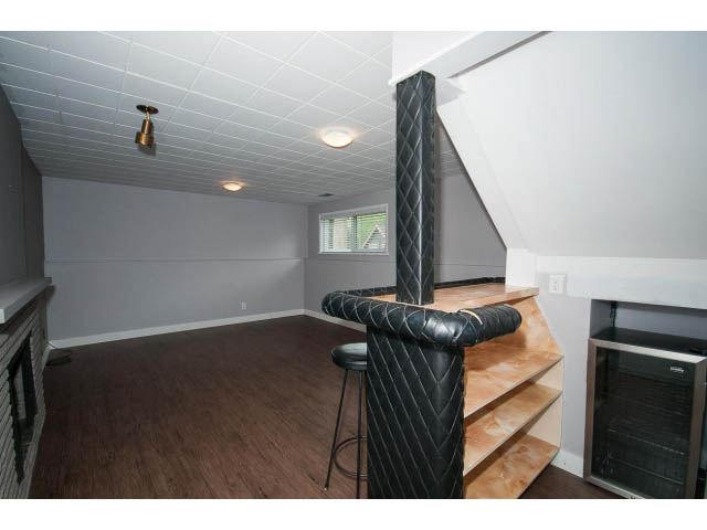 Furnished living room with hardwood floors and a black leather sofa. - 3188 St. Andrews Ave, North Vancouver