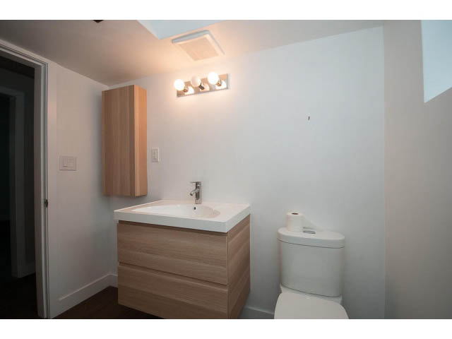 Bright bathroom with modern sink, light wood cabinets, and white walls. - 3188 St. Andrews Ave, North Vancouver