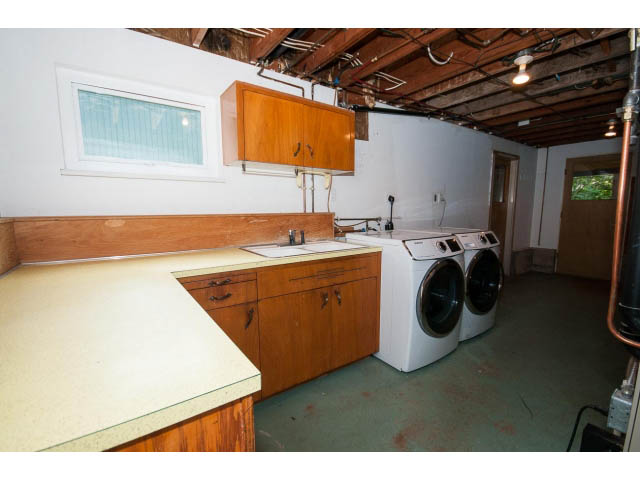 Laundry room with wooden cabinets and countertop, exposed ceiling. - 3188 St. Andrews Ave, North Vancouver