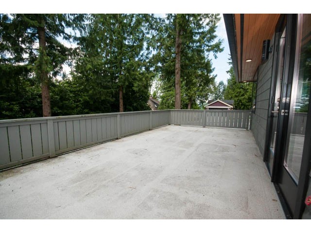 Spacious patio with wooden railing and lush greenery. - 3188 St. Andrews Ave, North Vancouver