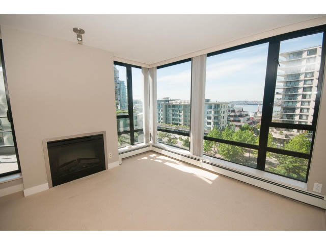 Bright living room with large windows offering a city view and a fireplace. - 701 - 151 West 2nd Street, North Vancouver
