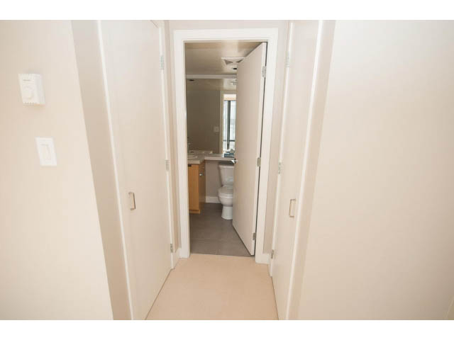 Furnished hallway leading to a small bathroom with a toilet and sink. - 701 - 151 West 2nd Street, North Vancouver
