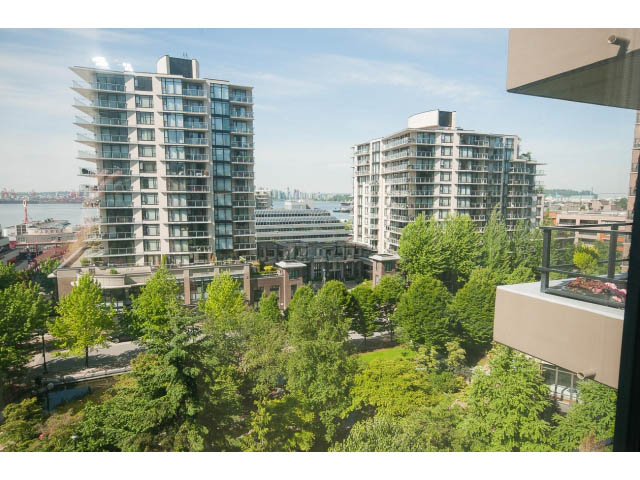 Bright living room with city view and lush greenery. - 701 - 151 West 2nd Street, North Vancouver