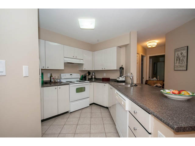 Bright kitchen with granite countertops, white cabinets, and a city view. - 201 - 150 West 22nd Street, North Vancouver