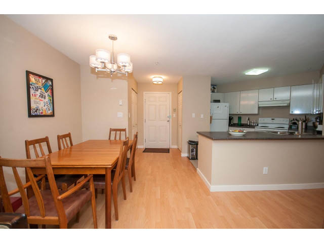 Bright dining and kitchen area with hardwood floors and modern appliances. - 201 - 150 West 22nd Street, North Vancouver