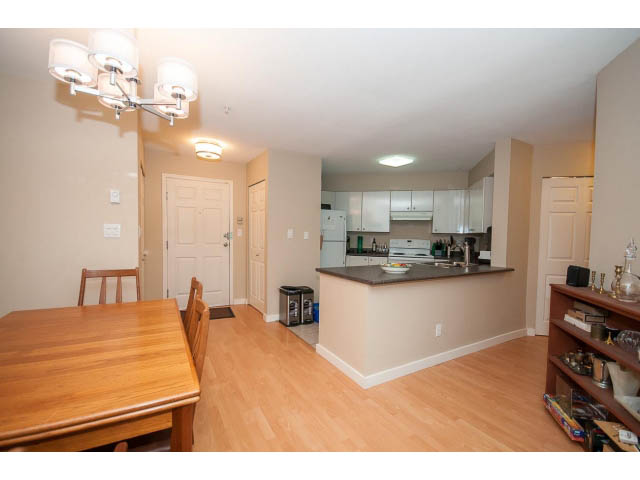 Bright kitchen with light wood countertops and hardwood floors, open to dining area. - 201 - 150 West 22nd Street, North Vancouver