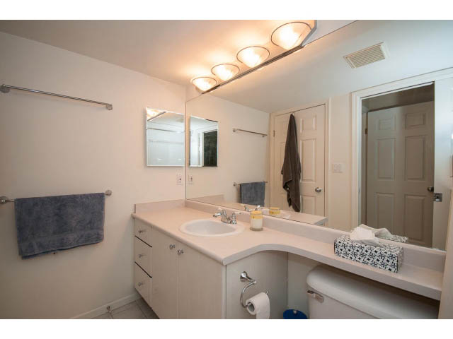Bright bathroom with white countertops and a large mirror above the sink. - 201 - 150 West 22nd Street, North Vancouver