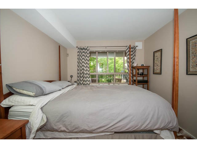 Spacious bedroom with a large bed, neutral decor, and a window with curtains. - 201 - 150 West 22nd Street, North Vancouver