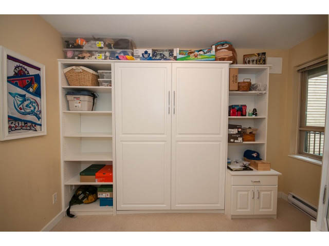 Bright laundry room with white cabinets, countertop, and storage shelves. - 201 - 150 West 22nd Street, North Vancouver