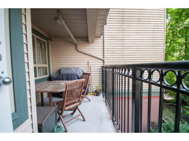 Furnished balcony with wooden chairs and railing, leading to a patio area. - 201 - 150 West 22nd Street, North Vancouver